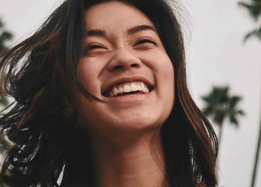 woman smiling with palm trees in the background