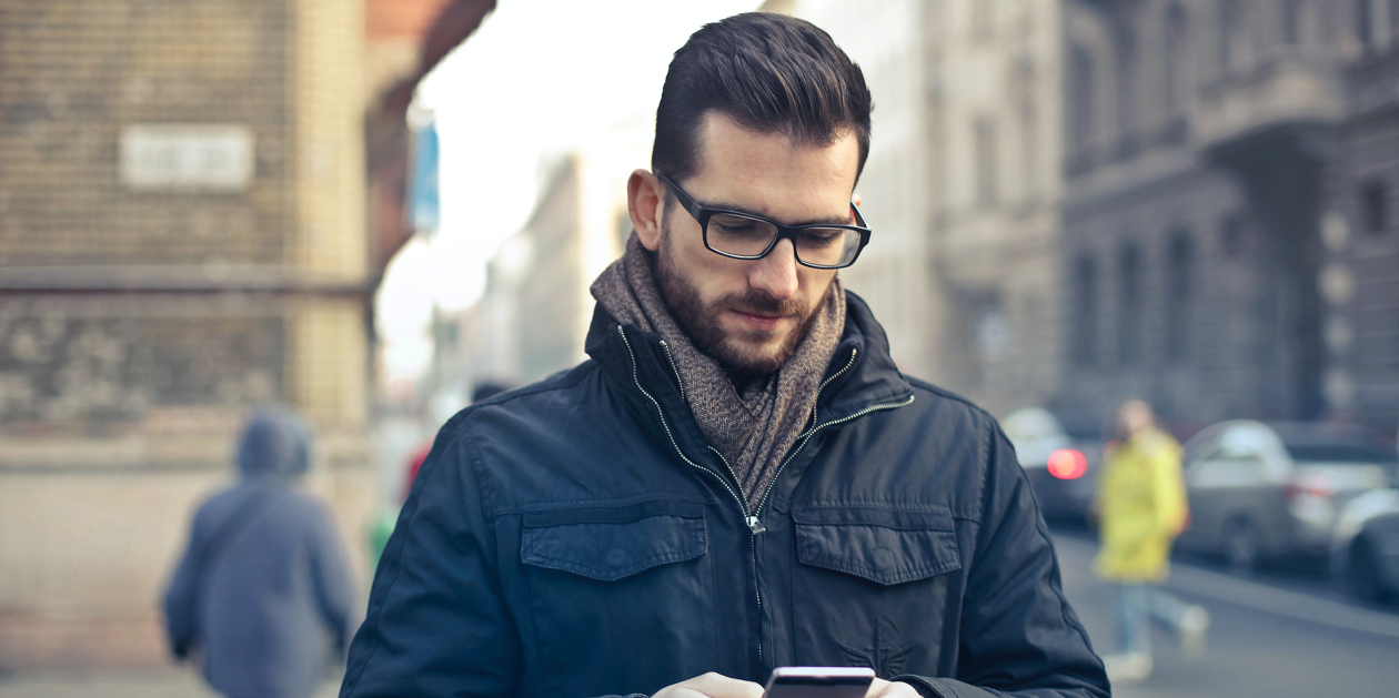 A man using his phone on a busy street.