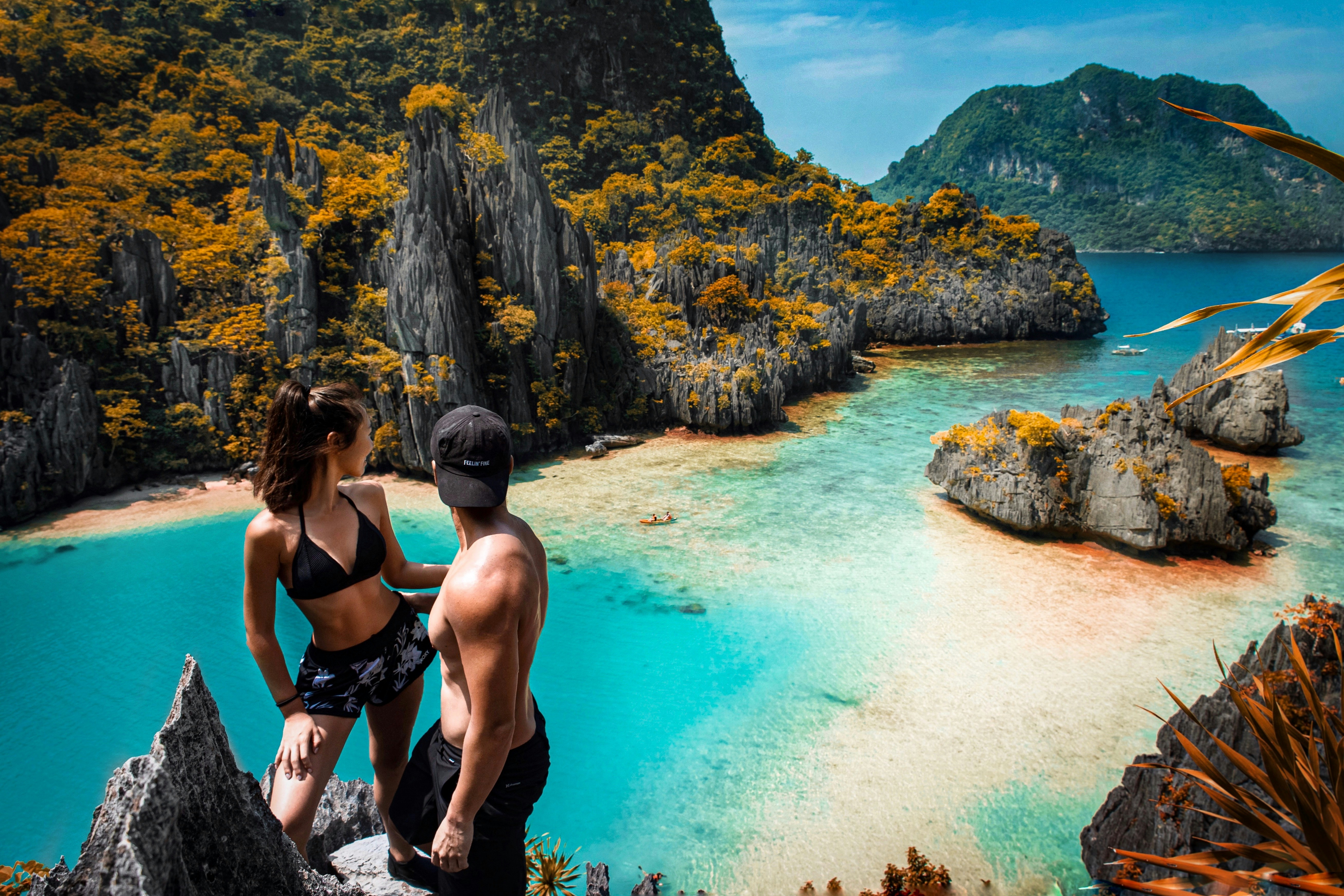 A couple looking at the ocean from the top of a rock formation.