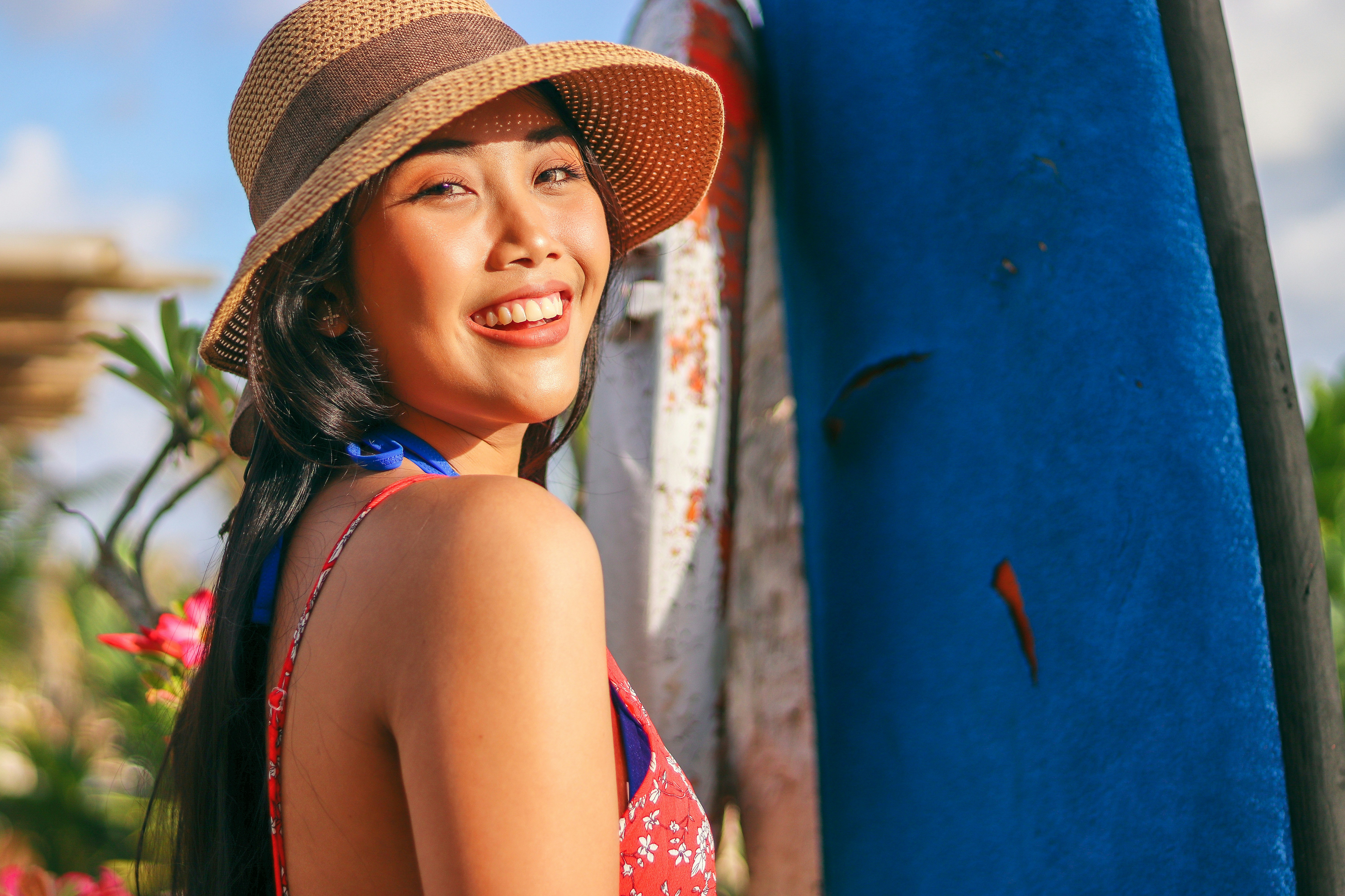 A beautiful Filipina wearing a woven hat smiling at the camera.