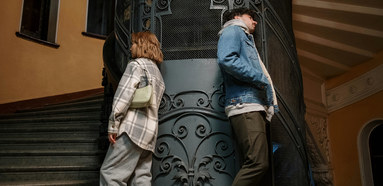 A man and woman standing with their backs to each other.